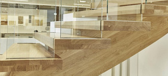 Moderne Holztreppe mit Glasgeländer und massiven Stufen aus Eichenholz in zeitgemäßem Design.